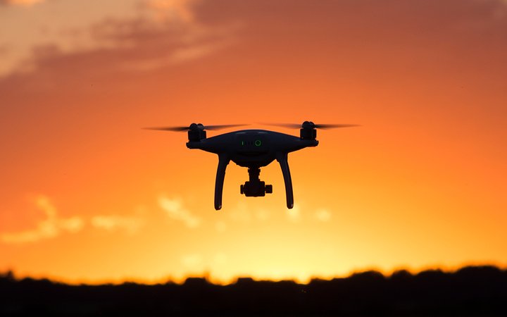 En drönare flyger i soluppgång.