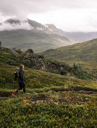 kvinna vandrar bland dimmiga bergstoppar
