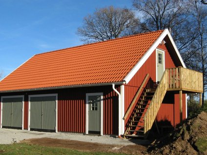 rött garage med två slagportar och en övervåning