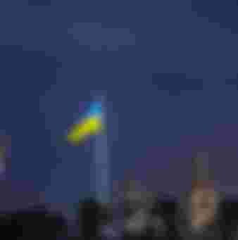 The national flag of Ukraine above the Kyiv skyline.