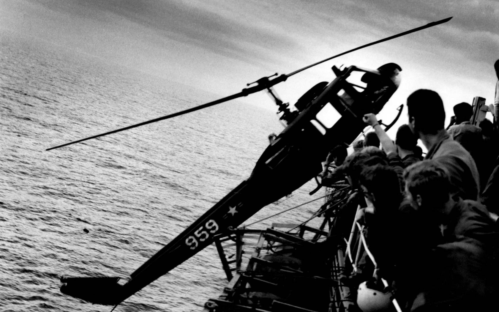 A helicopter is pushed off the overcrowded deck of the aircarft carrier USS Hancock (CV-19) off the coast of South Vietnam during the fall of Saigon.