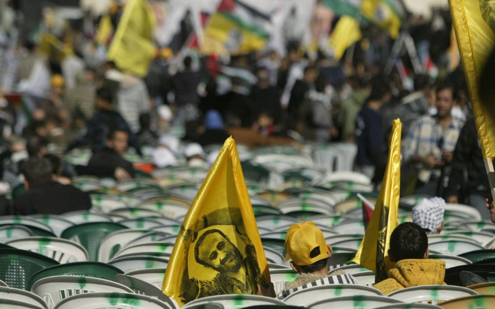 Palestinian youths carrying flags with an image of Marwan Barghouti.