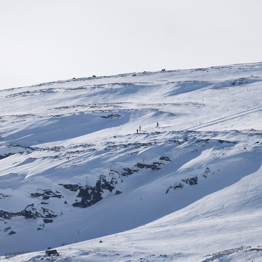tre offpist&aring;kare i fj&auml;rran vid ett berg i Bj&ouml;rkliden