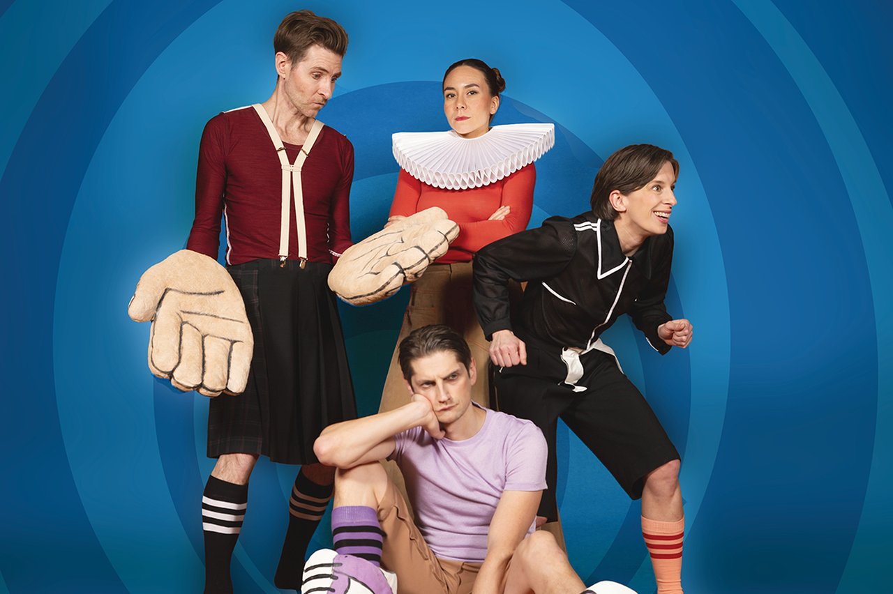 Fyra personer i lekfulla, stiliserade kostymer poserar tillsammans mot blå bakgrund, med överdimensionerade accessoarer och uttrycksfulla poser.