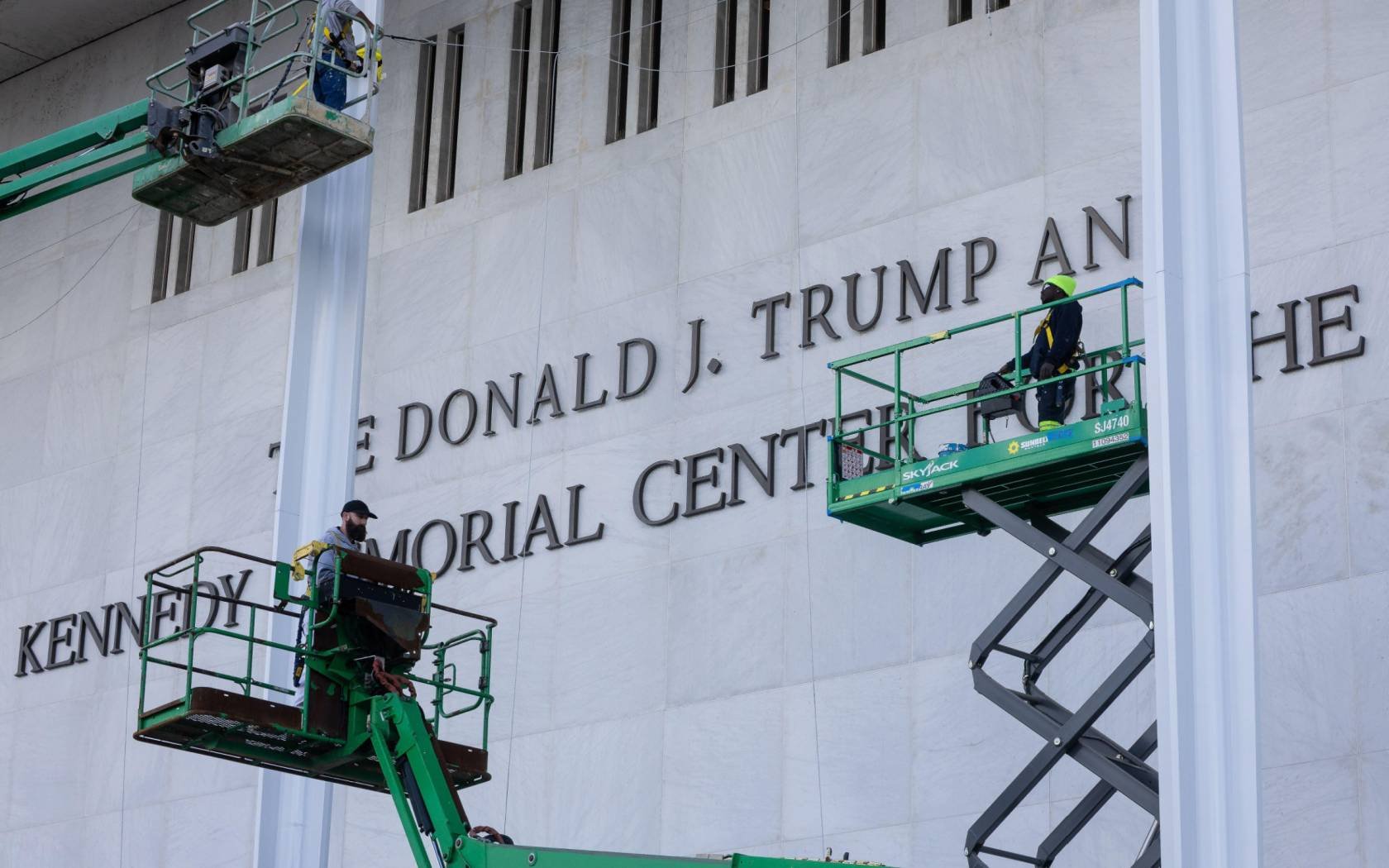 Workers add the name of President Donald Trump to the exterior of the John F. Kennedy Center for the Performing Arts in Washington, D.C.