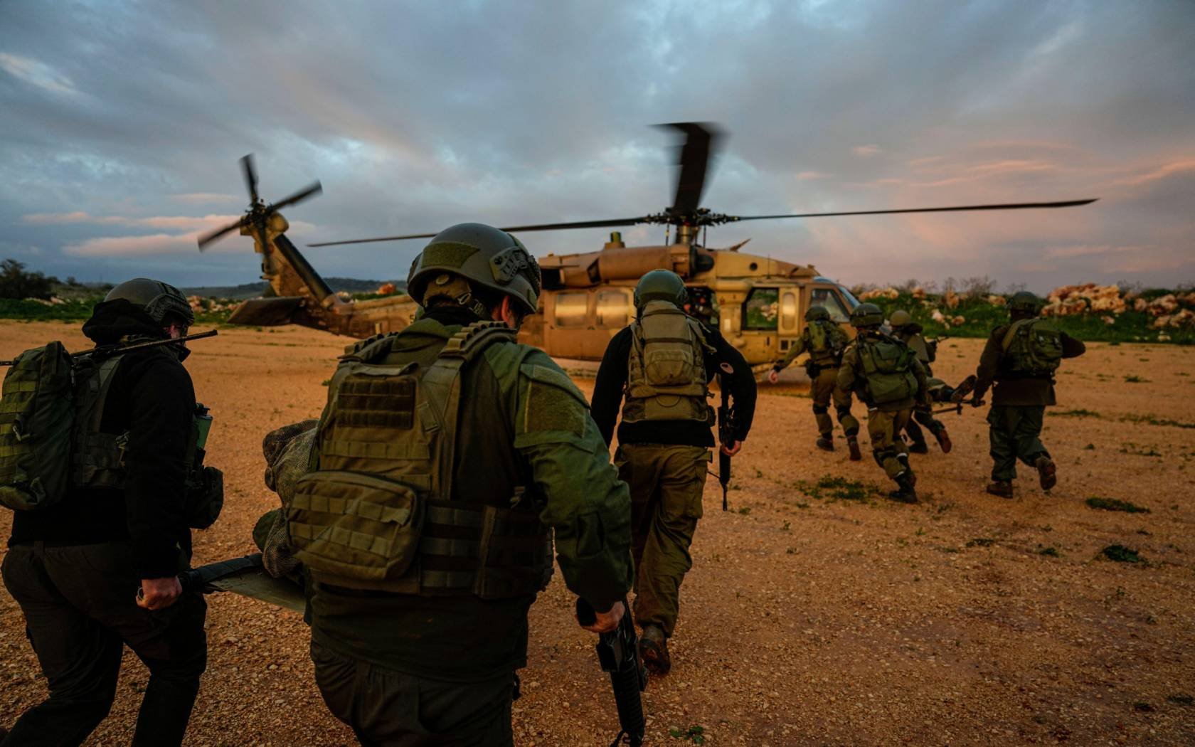 Israeli soldiers run as they carry stretchers towards a military helicopter during an exercise simulating the evacuation of wounded people in northern Israel, near the border with Lebanon in February, 2024.