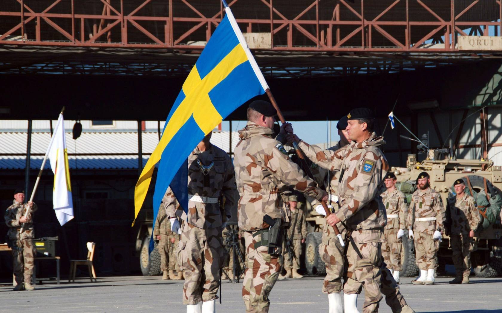 Swedish incoming commander Col. Micheal Claeasson, centre left, receives the Sweden flag from outgoing commander Col. Torbjorn Larsoon during a changing of command ceremony at the Provincial Construction Team compound in Mazar-i- Sharif, north of Kabul, Afghanistan, 2012.