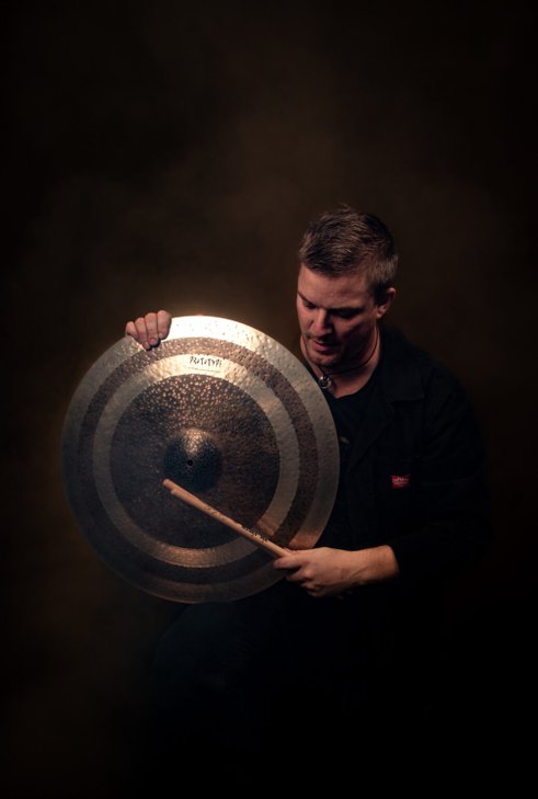 The troubadour Christopher Lidström holds up a cymbal