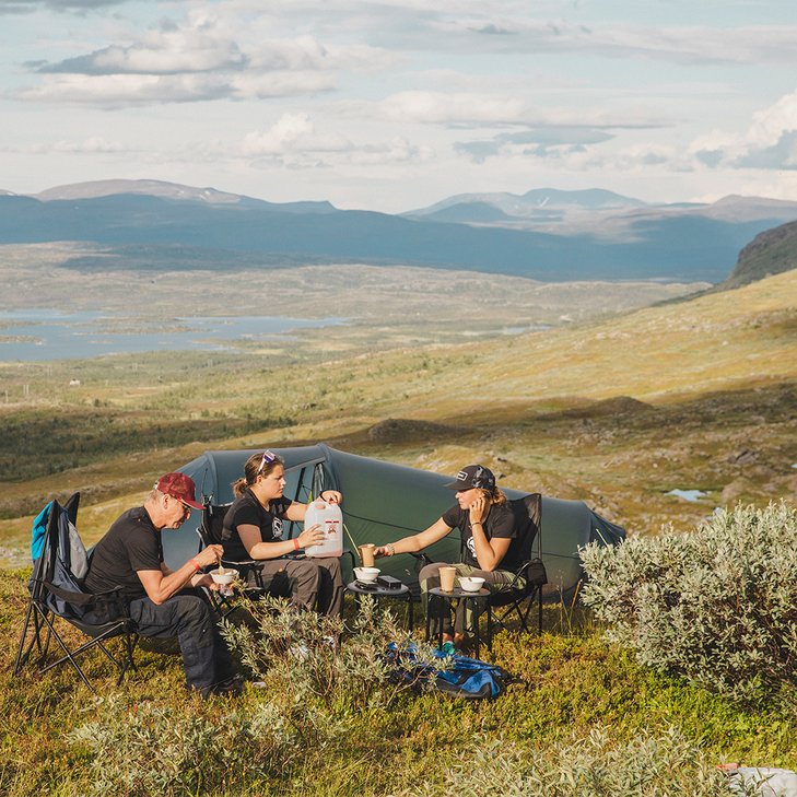 tv&aring; kvinnor och en &auml;ldre herre &auml;ter middag p&aring; fj&auml;llet vid sitt t&auml;lt