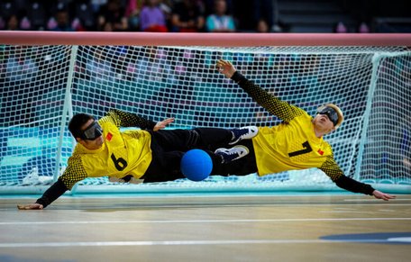 Två målvakter i goalball slänger sig åt varsitt håll och räddar bollen.