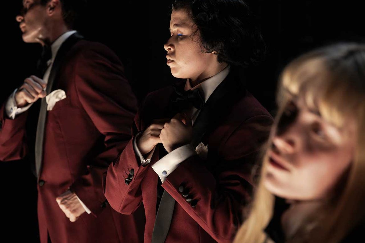 Tre personer i röd smoking från föreställningen Burn Baby Burn.