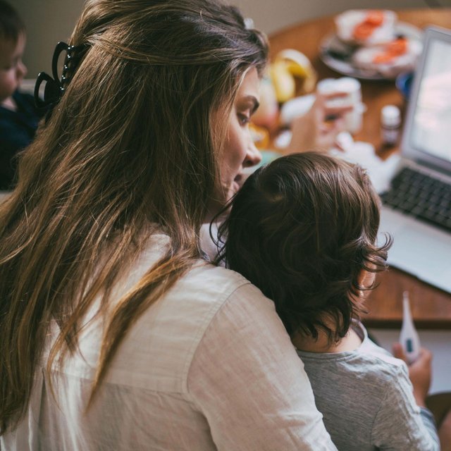 Mother with sick son taking advice from male doctor on video call at home
