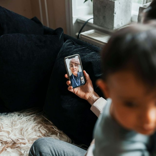 High angle view of female pediatrician assisting woman through video call on smart phone at home