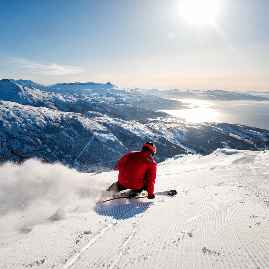 pist&aring;kare carvar s&aring; att sn&ouml;n yr med fjorden som utsikt i Narvik