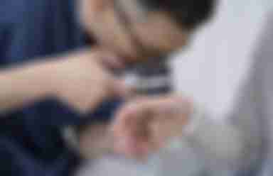 Manlig läkare undersöker kvinnlig hand med ortoskop