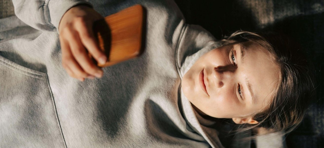 High angle view of young woman using smart phone while lying down with hand behind head