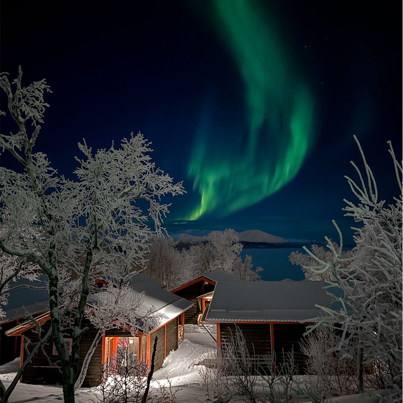 The Northern Lights dance above a frost-kissed cottage village