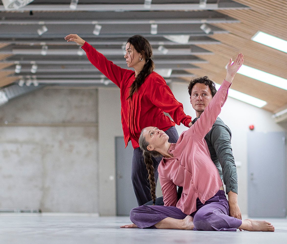 Tre dansare i ett kalt rum med takfönster.