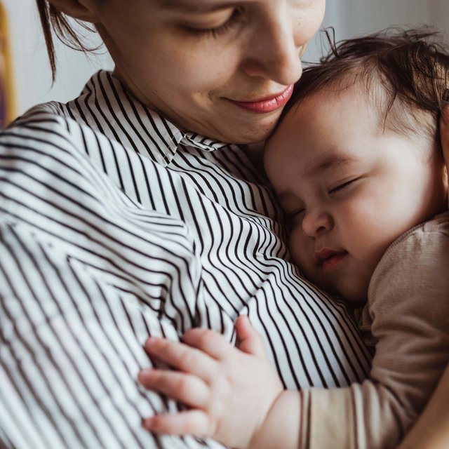 Mother looking at sleeping male toddler at home