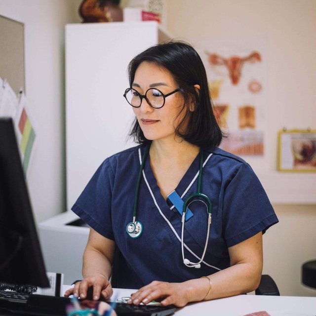 Smiling female healthcare expert using computer sitting at desk in office