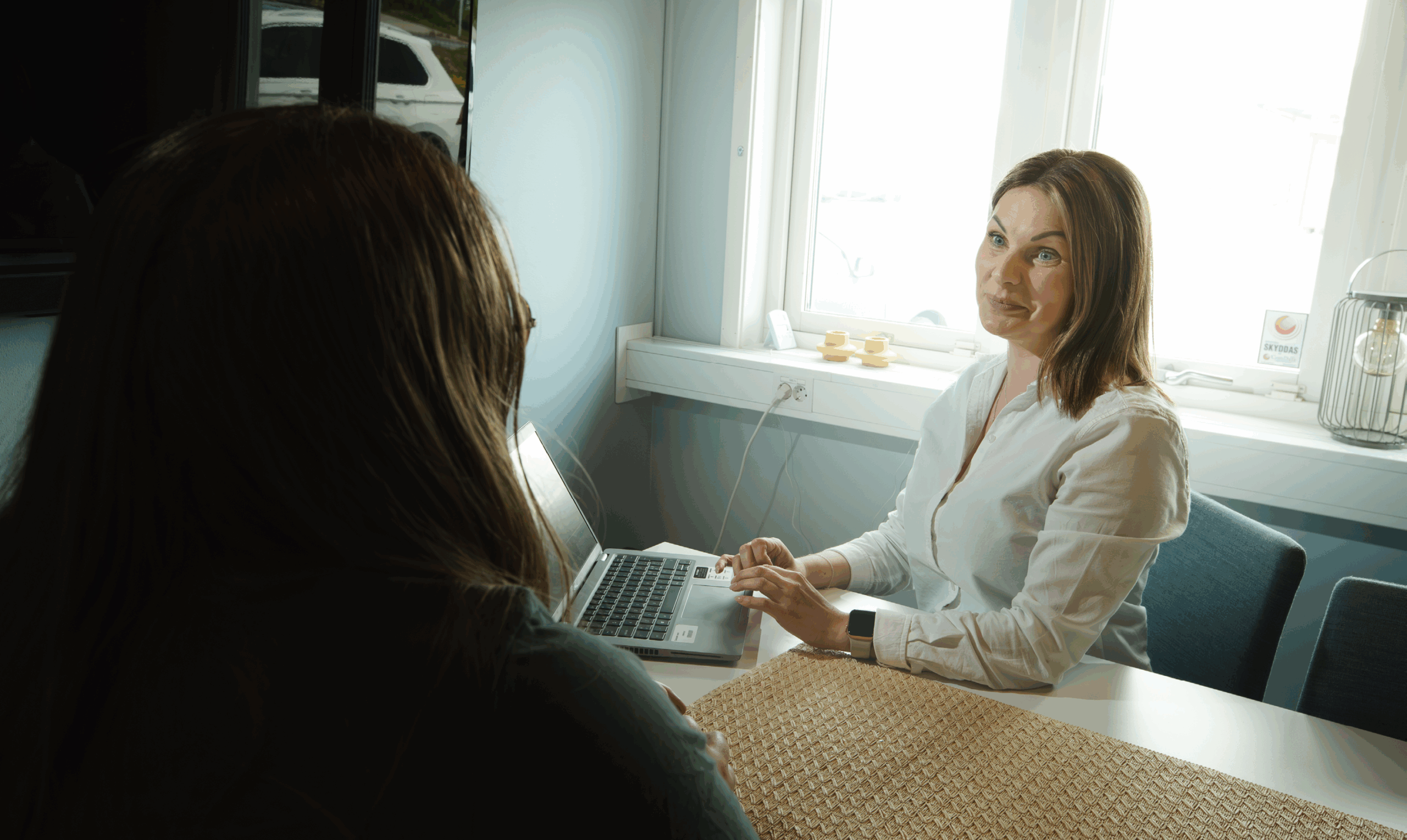 Tv&aring; personer sitter vid ett bord och pratar