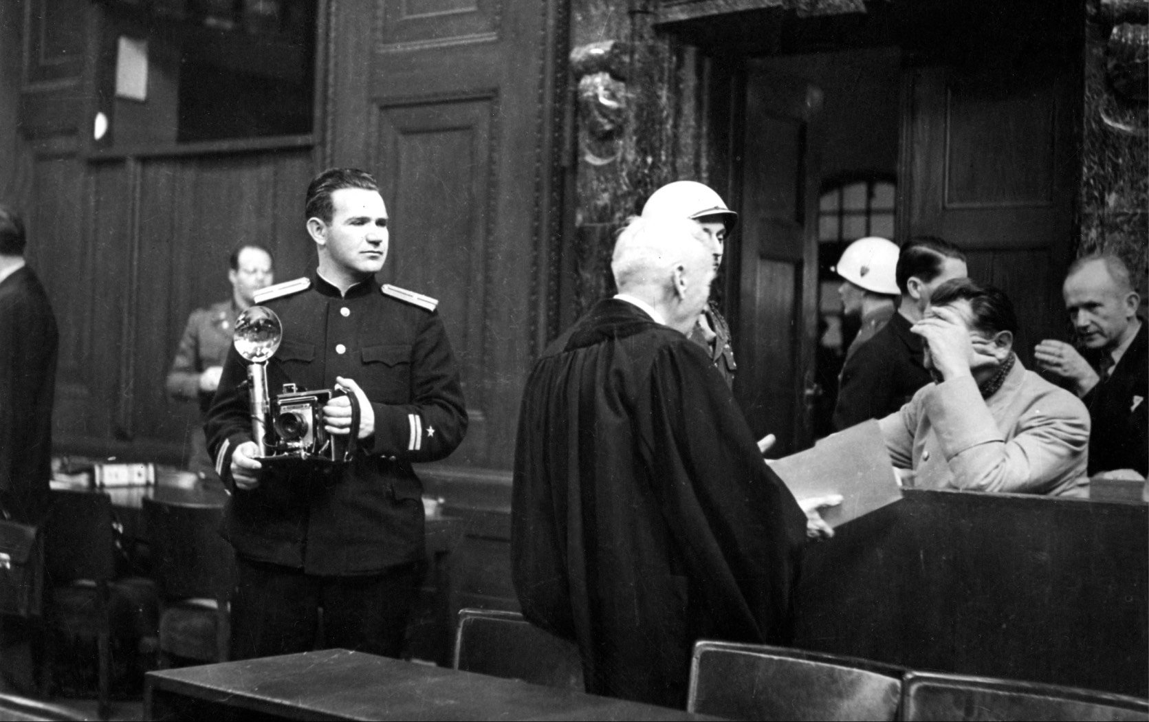 Soviet photographer Yevgeny Khaldei in the court room of the Nuremberg Trials while main defendant Hermann Goering covers his face with his hand. Credit: dpa picture alliance