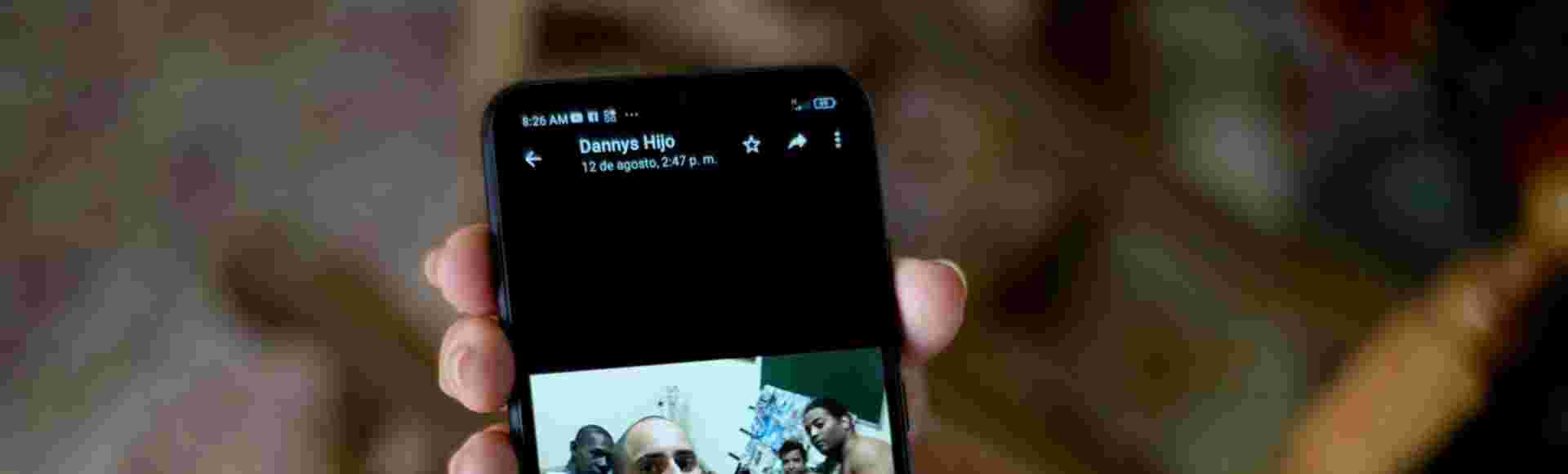 Marilin Vinent holds a photo of her son Dannys Castillo with other Cubans in Russia. Vinent said that her son travelled to Russia after being promised work in a construction job but that he was one of the Cubans recruited to fight for Russia in Ukraine. Credit: Ramon Espinosa