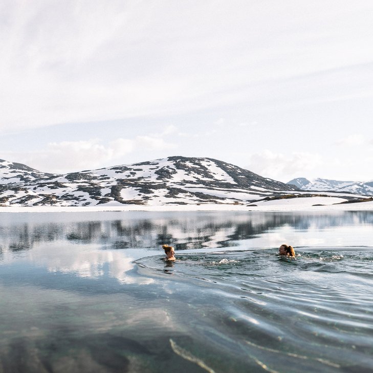 tv&aring; kvinnor fj&auml;llbadar med sn&ouml;fl&auml;ckade berg i bakgrunden