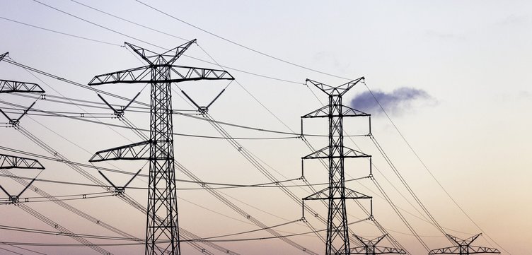 A row of dark power lines stands out against a vibrant sunset.