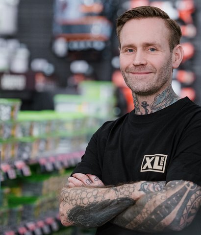 tatovert ansatt i XL-BYGG smiler mot kamera