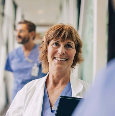 Female mature physician looking away while standing in hospital