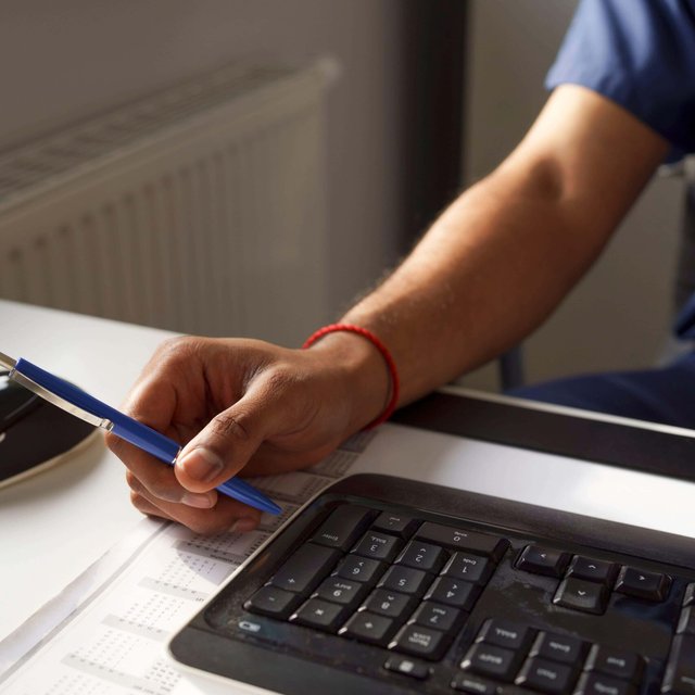 Male healthcare worker holding pen near keyboard at desk in hospital