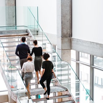 Rear view of group of young businesspeople walking up the stairs.