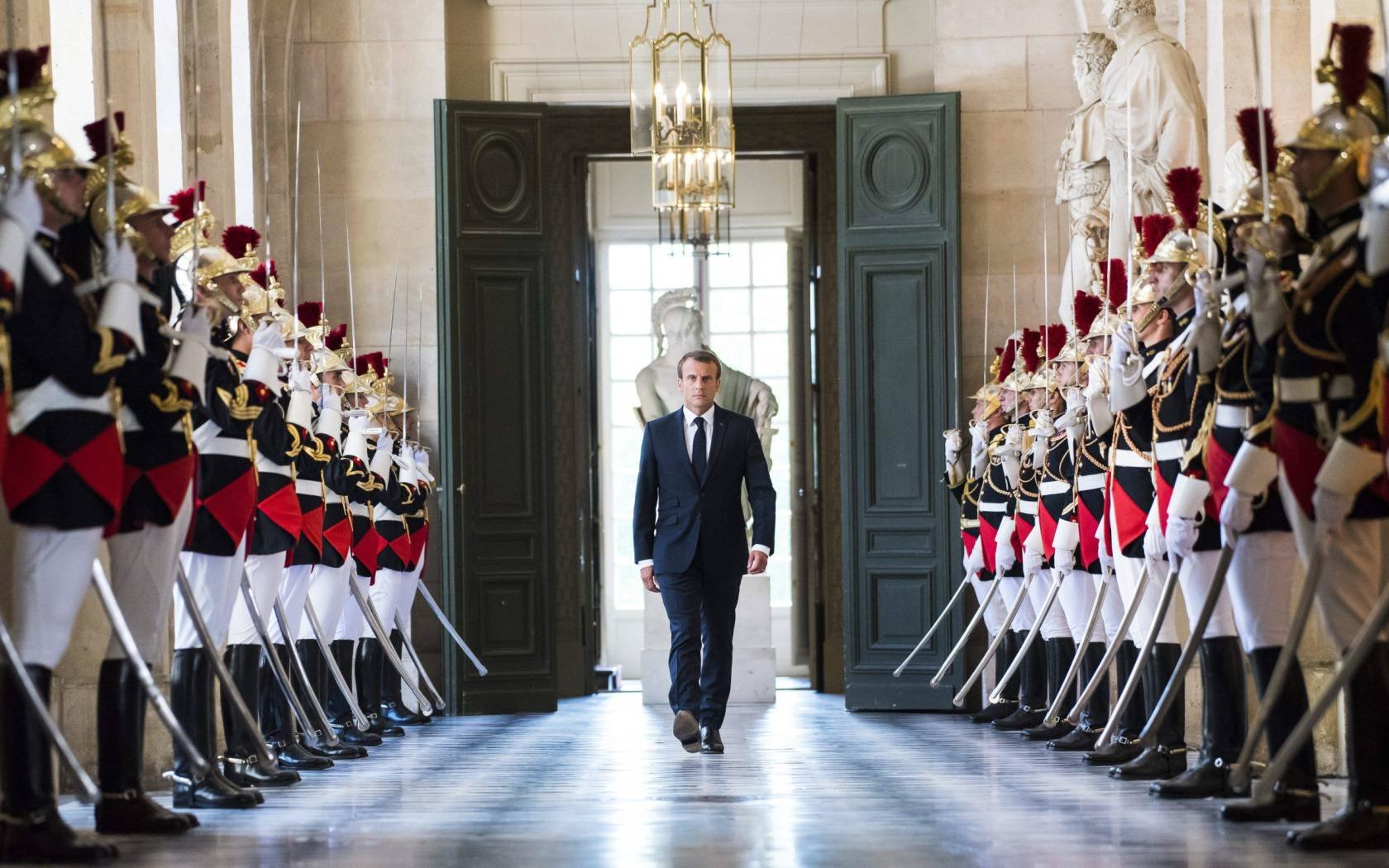 French President Emmanuel Macron walks through the Galerie des Bustes at Versailles.
