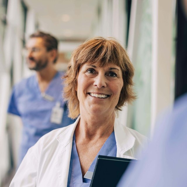 Female mature physician looking away while standing in hospital