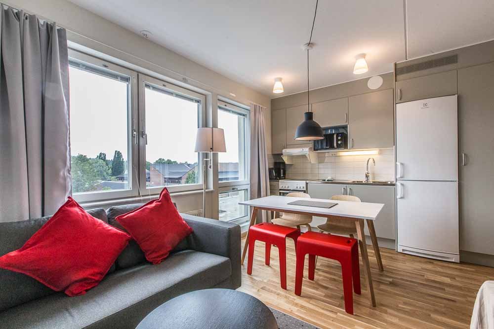 Apartment with couch, table, chairs. Kitchen with refrigerator, freezer, stove, oven, microwave, sink and cupboards.