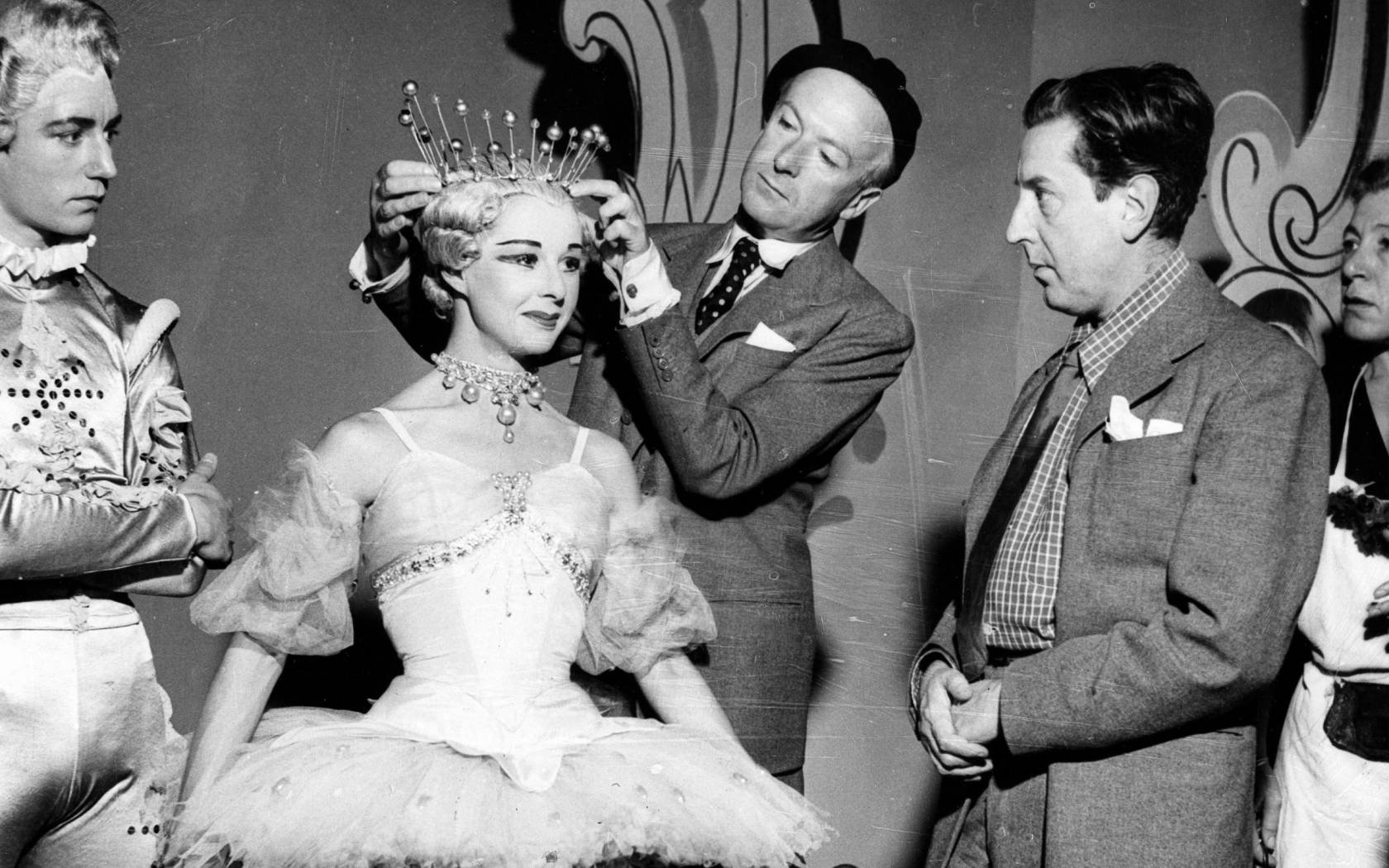 Cecil Beaton adjusting a headpiece backstage.
