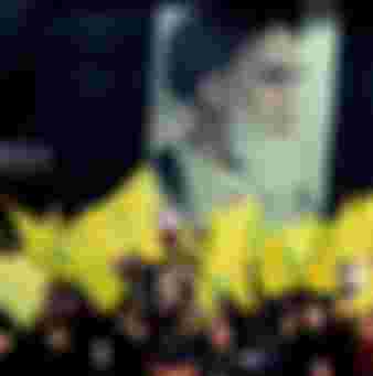 Supporters of the pro-Iranian Lebanese Hezbollah group wave the party flags in front of a poster of late Iranian leader Ayatollah Khomeini during a ceremony in Beirut.