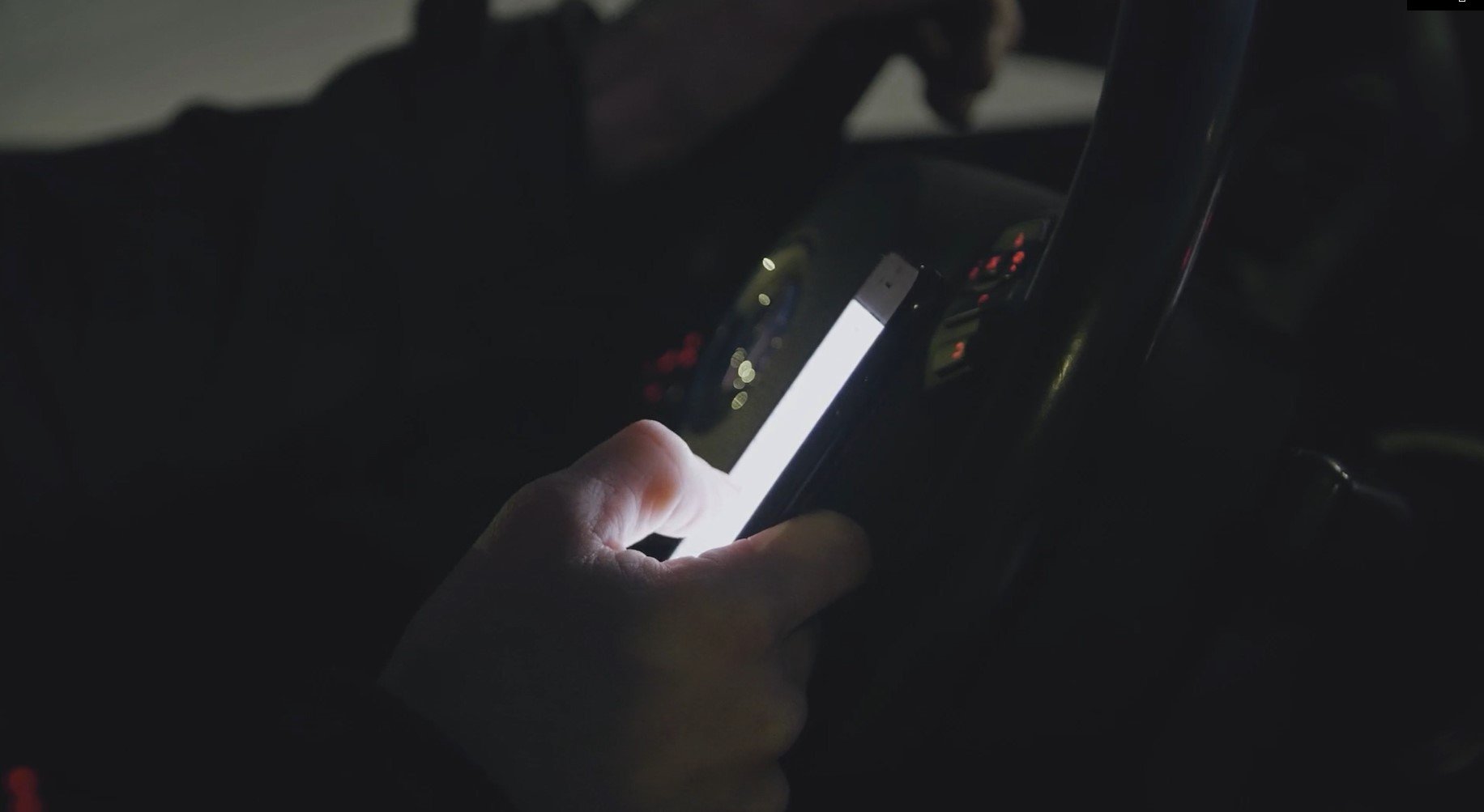Person knappar på mobilen i en bil i mörker