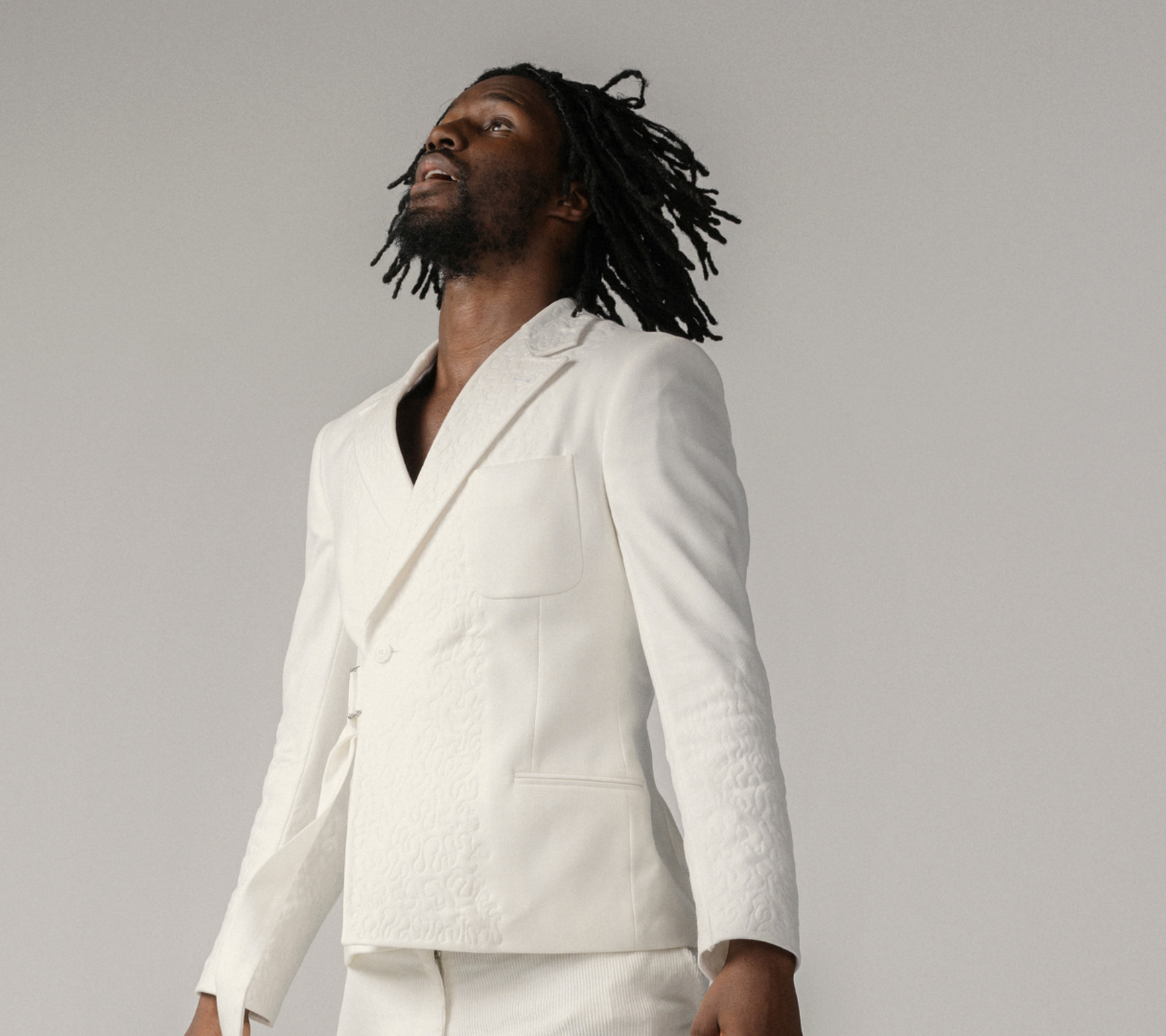 Dansaren hoppar rakt upp i luften med kroppen helt uppsträckt, armarna upp utmed kroppen och tittar upp mot himlen.