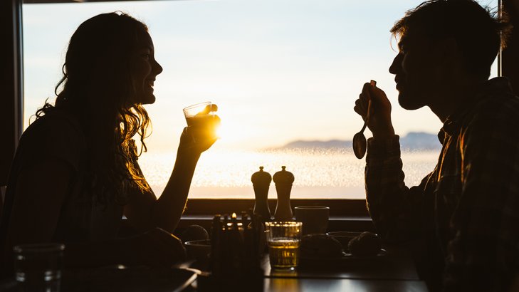 the sun shining through the window on a couple having breakfast