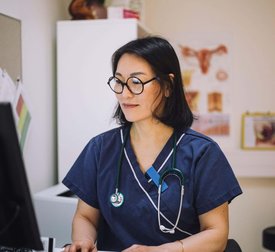 Smiling female healthcare expert using computer sitting at desk in office