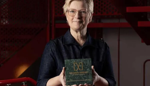 Anna Iwarsson står vid en röd trappa och håller i priset för månadens Nätängel.