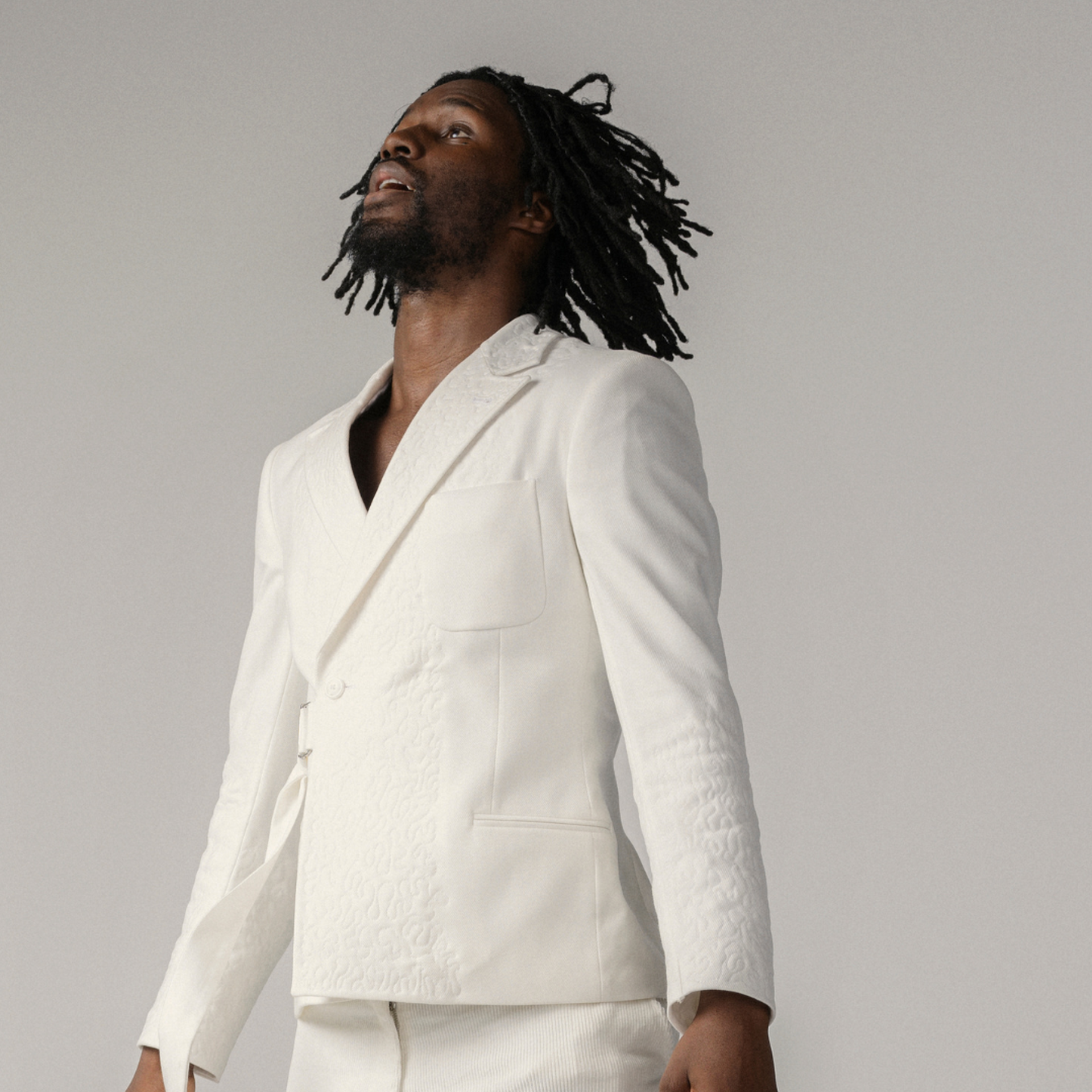 Dansaren hoppar rakt upp i luften med kroppen helt uppsträckt, armarna upp utmed kroppen och tittar upp mot himlen.