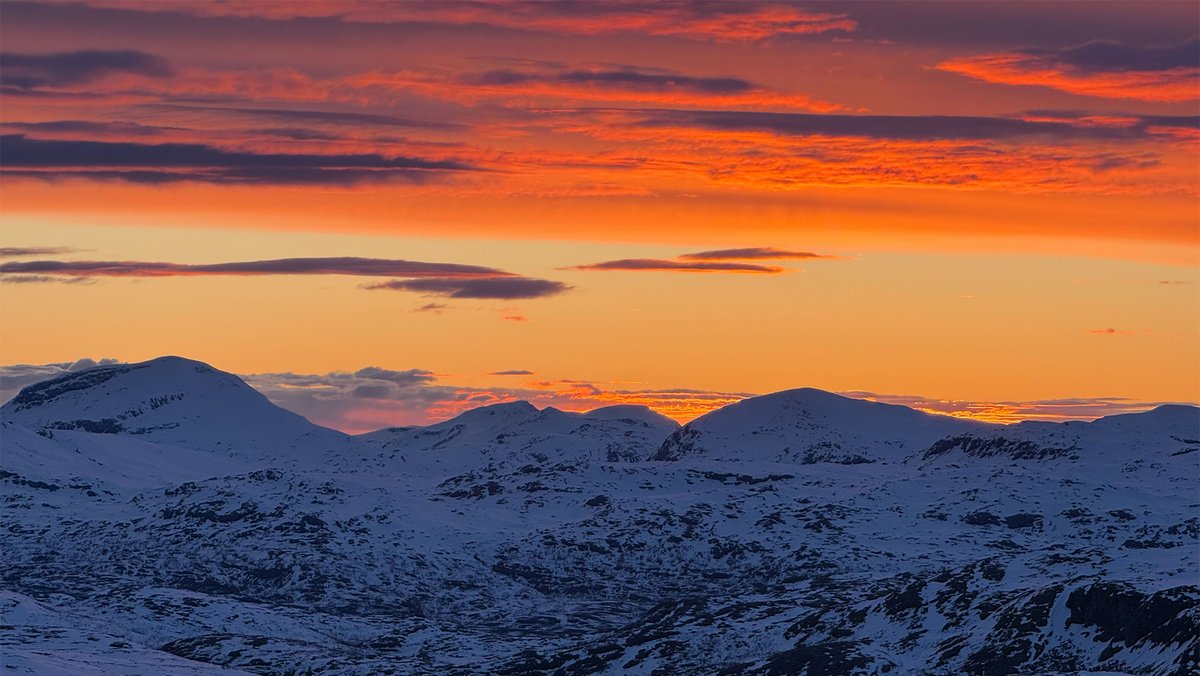 glowing midnight sun behind the mountain peaks