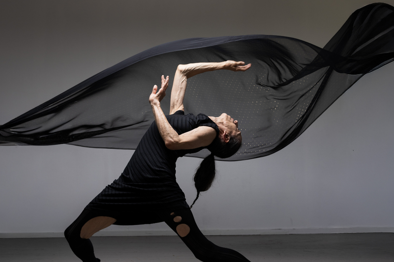 Dansaren Nathalie tittar upp mot taket och ett genomskinligt tygstycke flyger omkring henne.