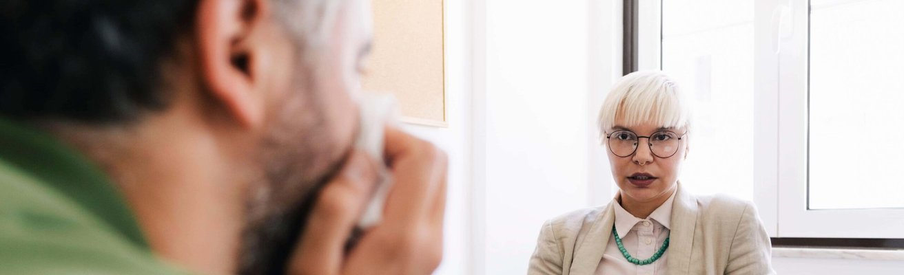 Kvinnlig psykoterapeut som samtalar med manlig patient sittande på ett terapikontor