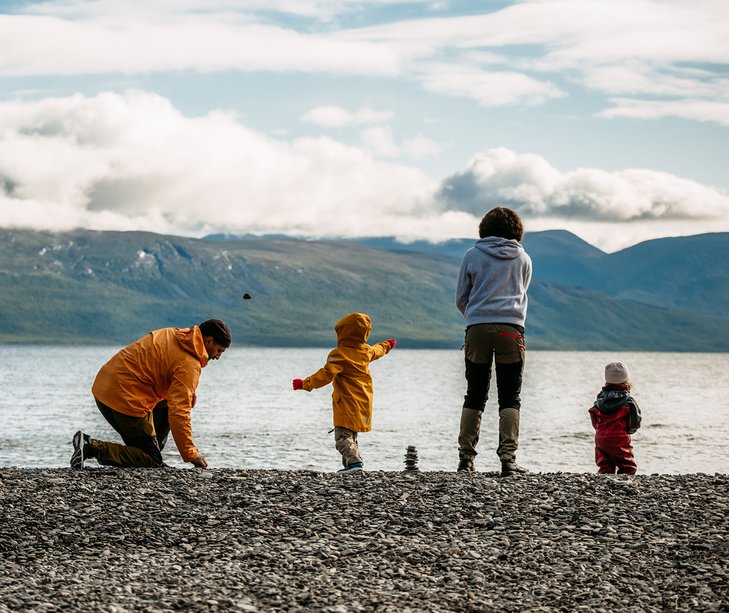 en barnfamilj kastar macka p&aring; stenstranden vid Tornetr&auml;sk och Silverfallet