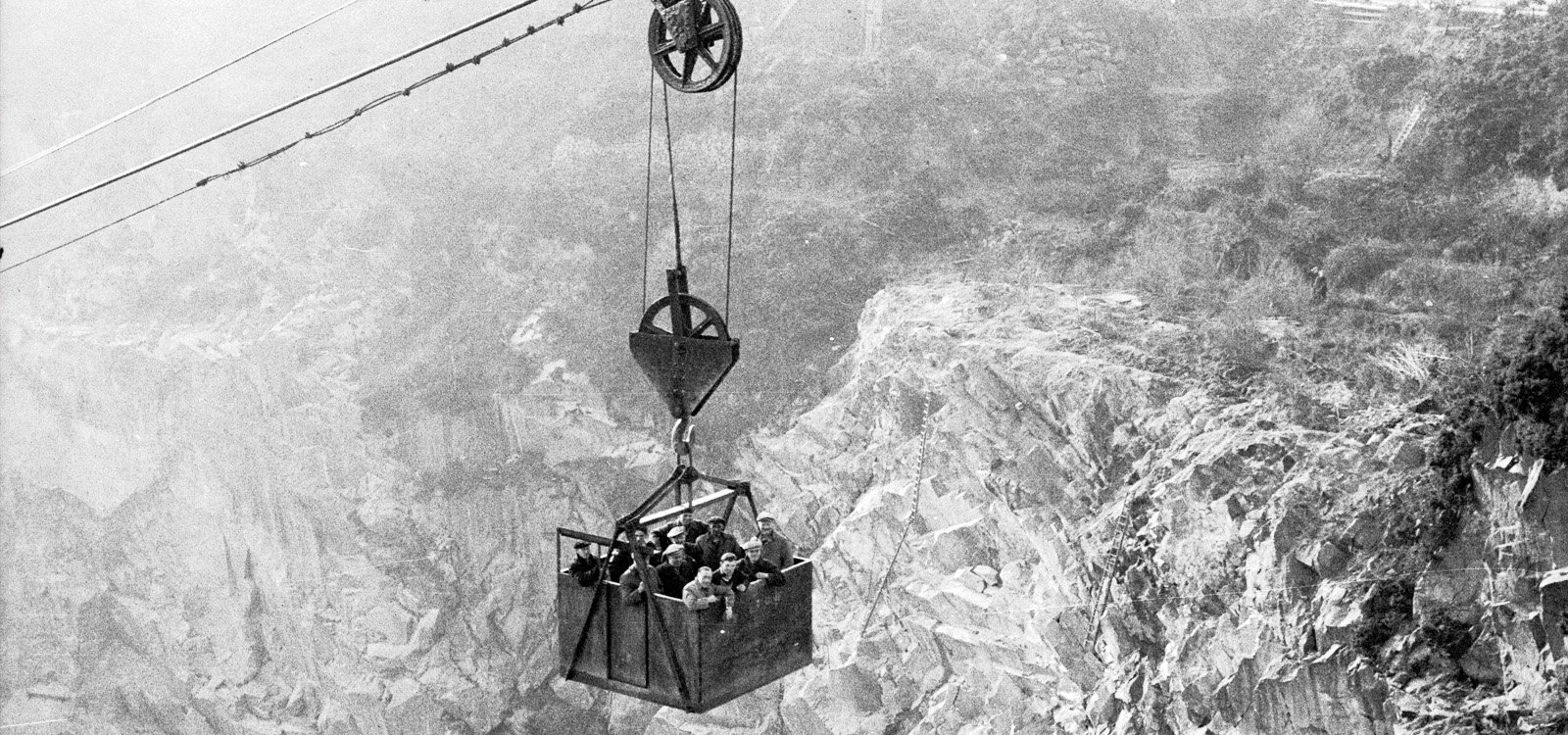 <p>Quarry workers in Wales catch a ride on a Blondin up from the floor of the pit.</p>
