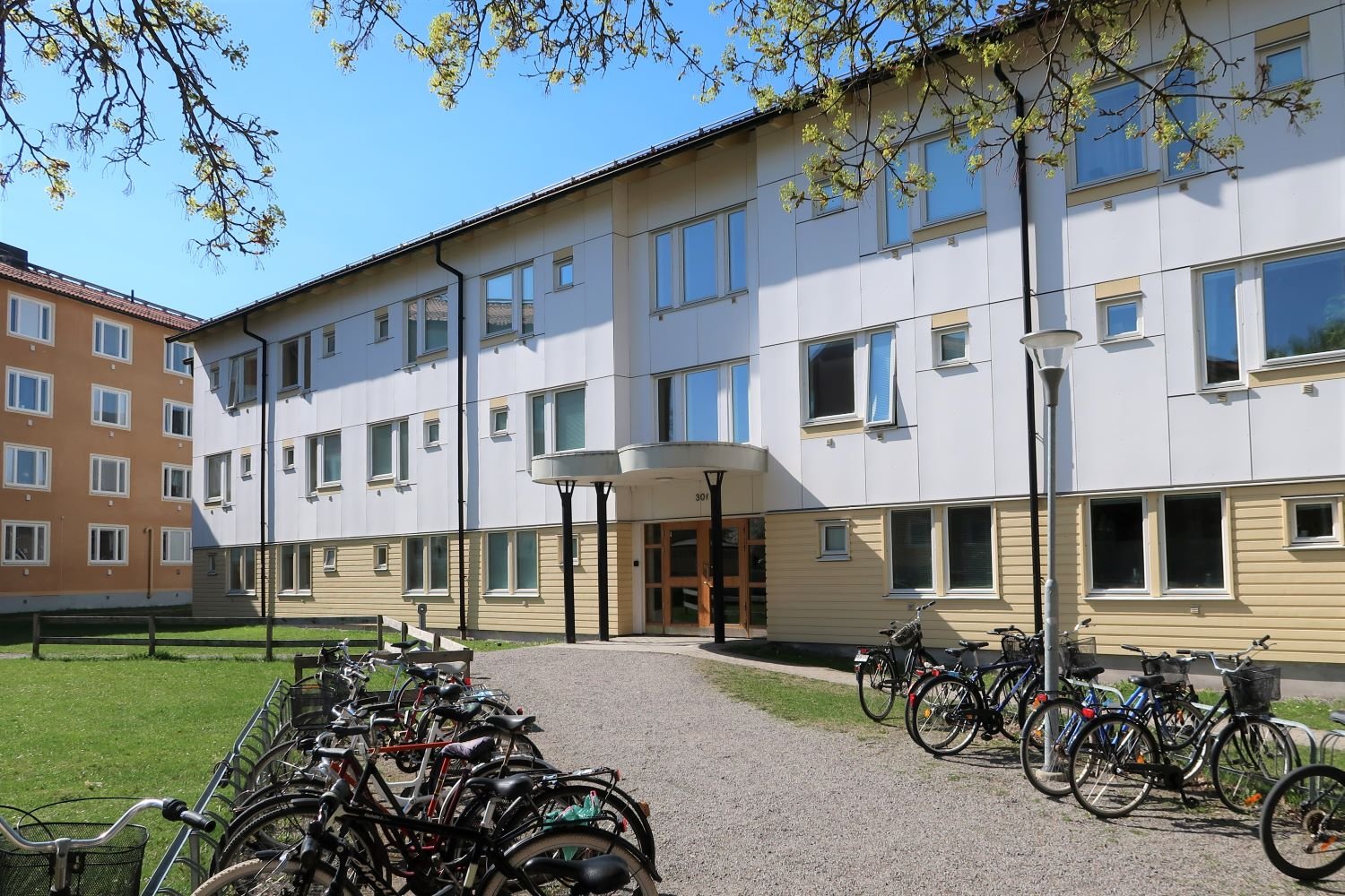 Exterior or white and yellow 3-story building with bicycle parking outside.